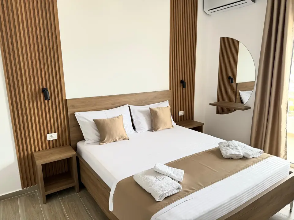 Deluxe Double Room with Balcony showing the full bed and modern wood interior
